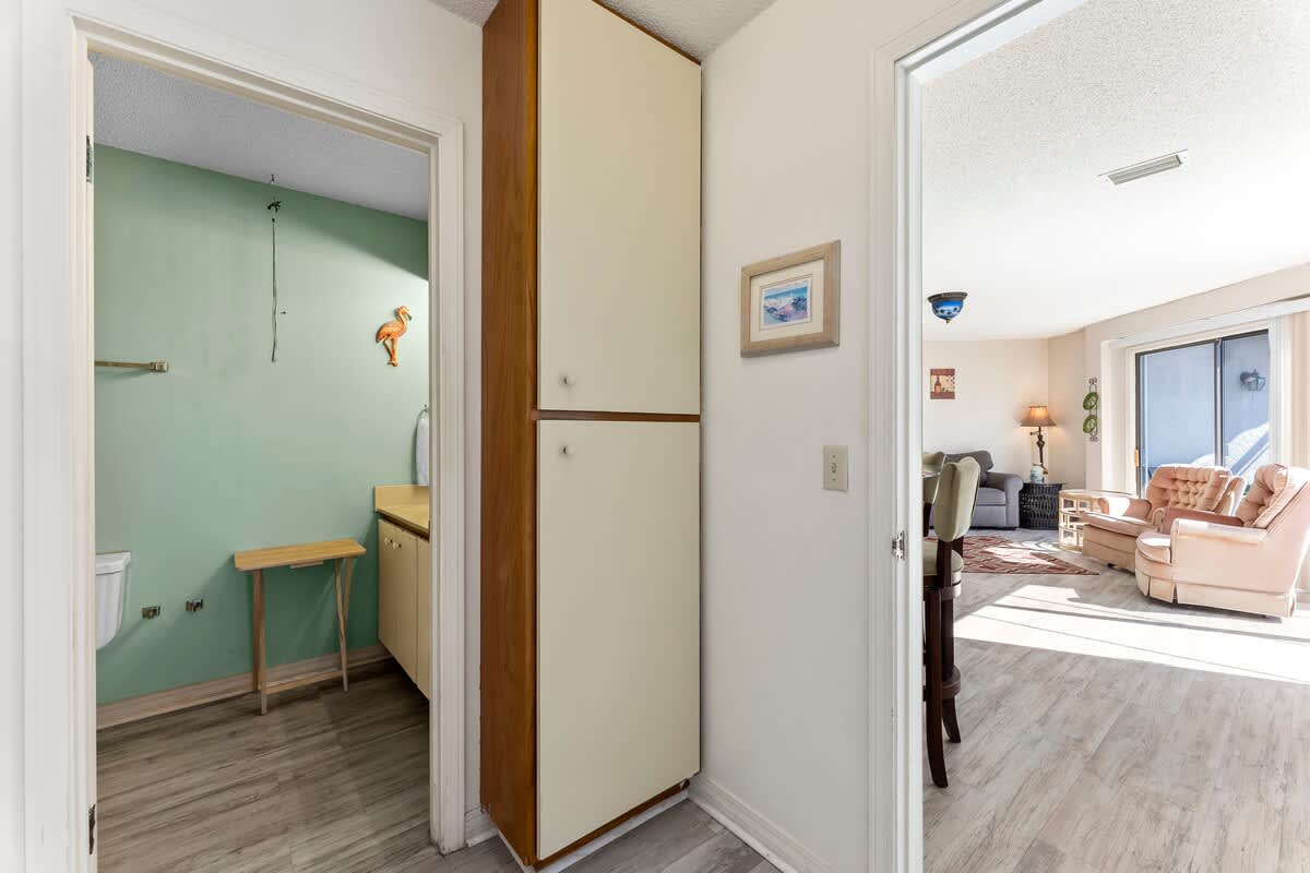 St Thomas SQ 1302B – Entry view into a vacation rental, showcasing a green wall bathroom and a living area with light furniture.