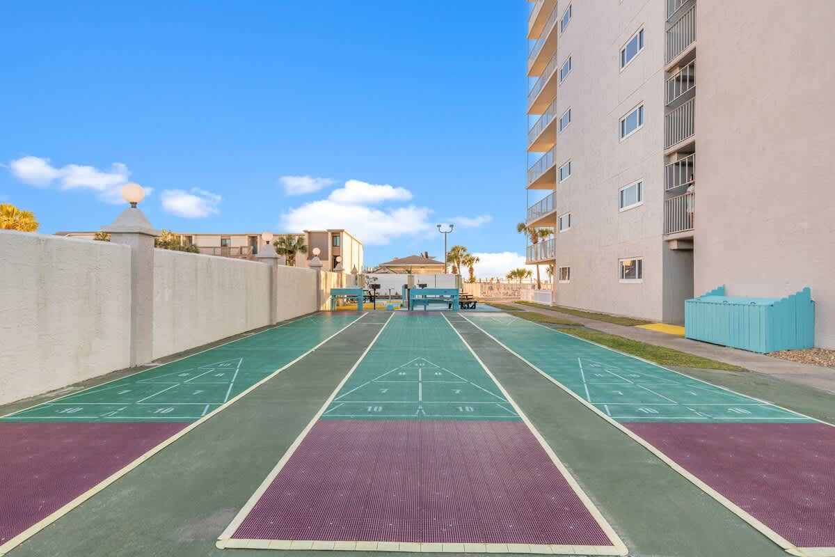 The Summit 1011 – Shuffleboard courts with a view of nearby buildings and palm trees under a blue sky.