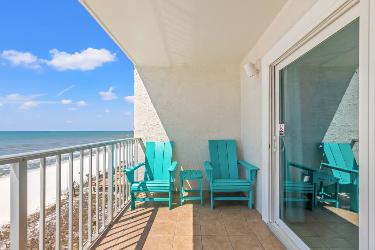 The Summit 1011 – Balcony with turquoise chairs overlooking the beach and ocean under a blue sky.