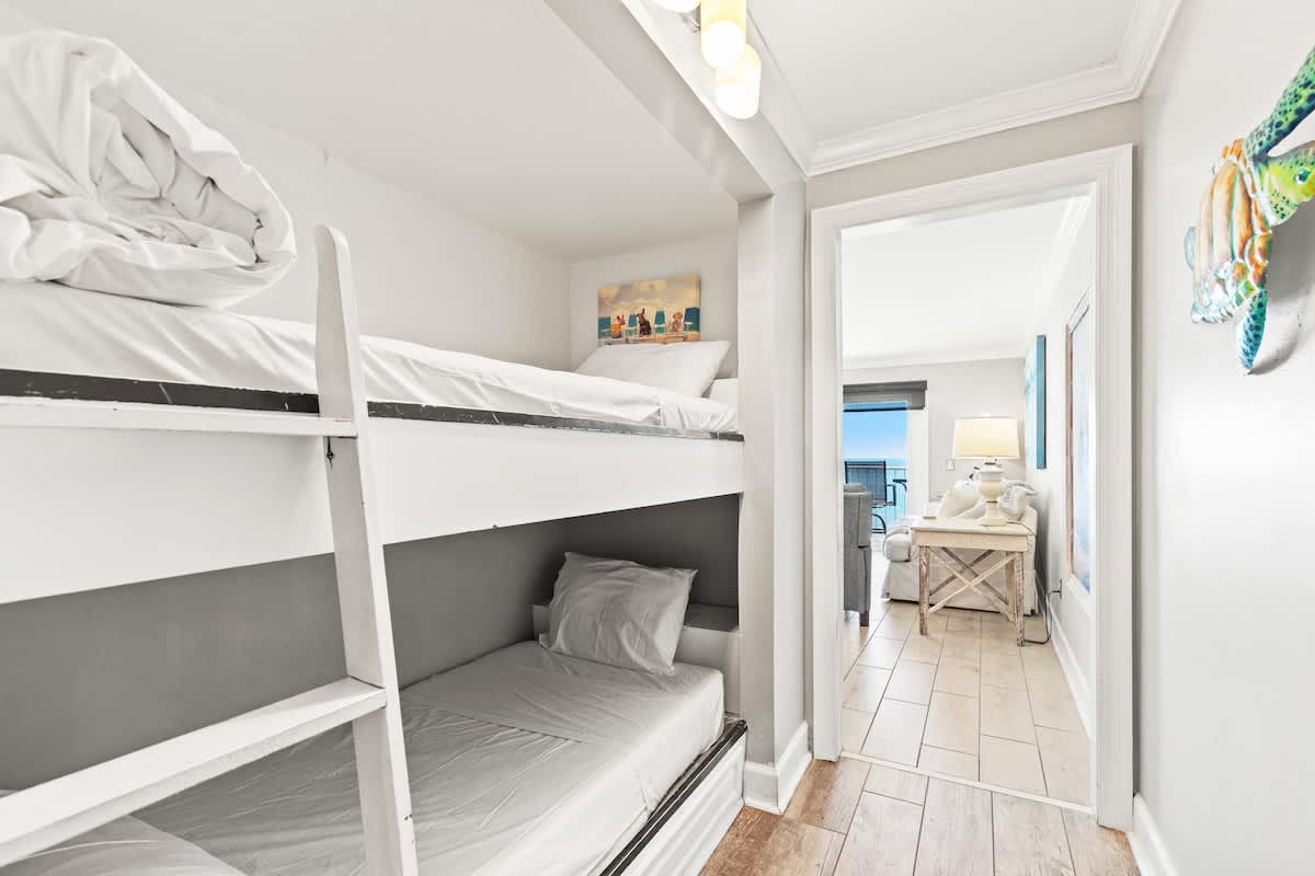 The Summit 1121 – Bunk bed area leading to a room with a view of the ocean and a light-filled interior.