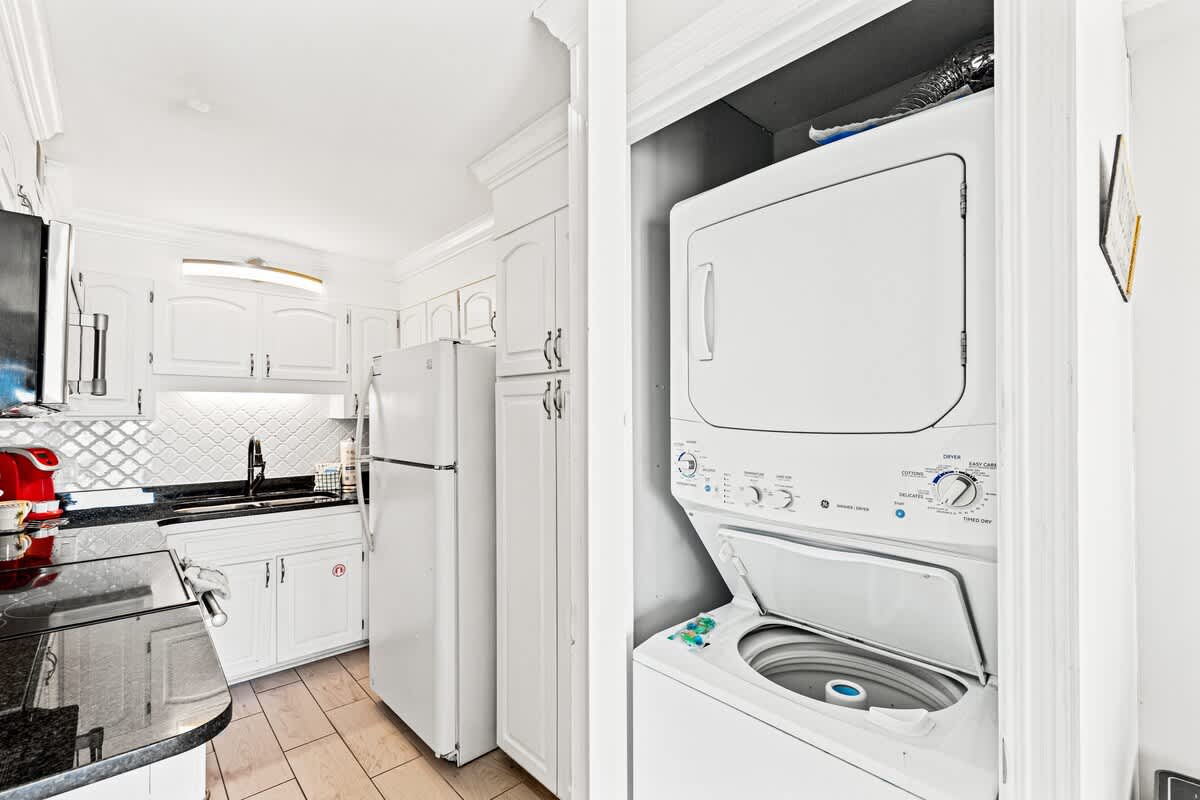 The Summit 1121 – Modern kitchen with white cabinetry, black countertops, and a stacked washer and dryer unit.