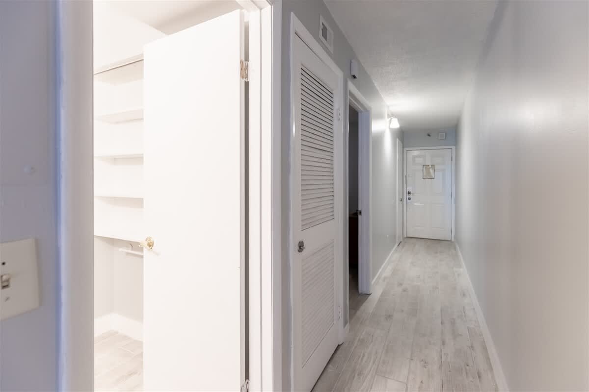 The Summit 618 – Narrow hallway with white doors, light-colored walls, and tiled flooring.