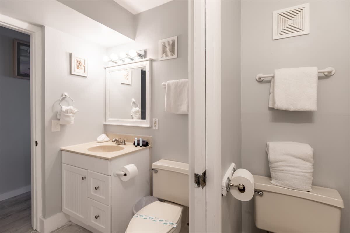 The Summit 618 – Bright bathroom with sink, mirror, toilet, and hanging towels.