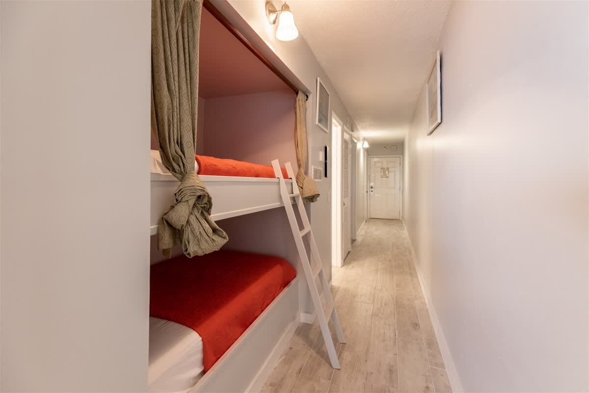 The Summit 618 – Bunk beds in a hallway with light-colored walls and wood flooring, leading to a door at the end.