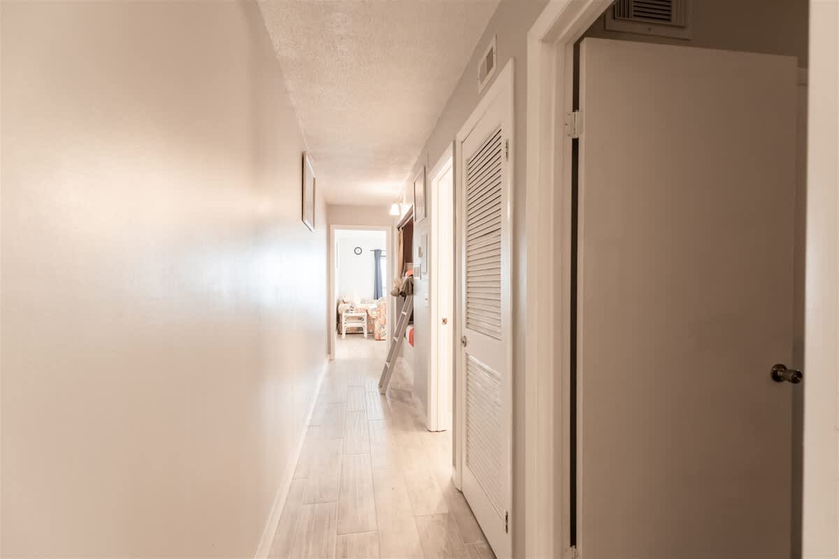 The Summit 618 – Long hallway with white walls, tile flooring, and doors leading to rooms.