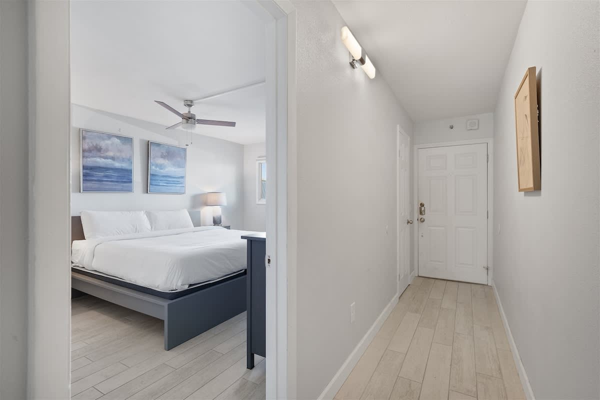 The Summit 220 – Hallway leading to a bedroom with a king bed, artwork, and a lamp.
