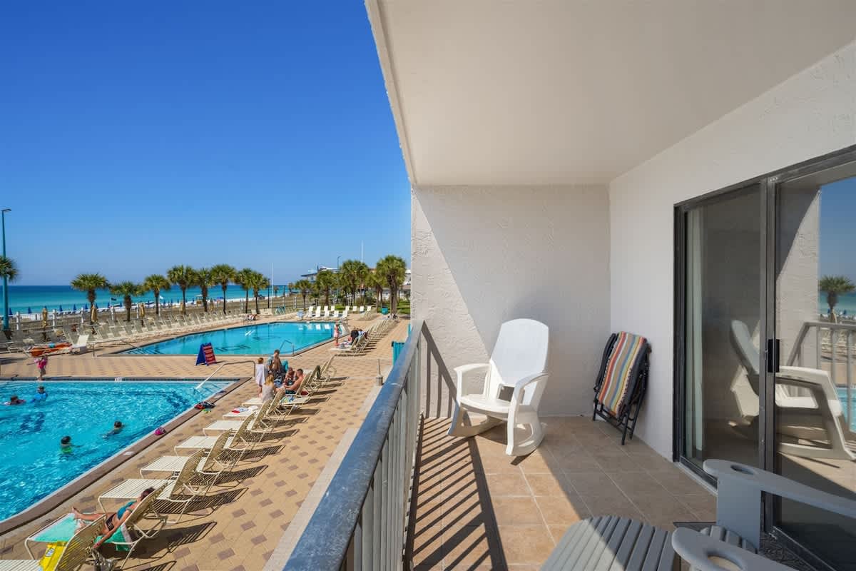 The Summit 220 – Balcony view of a pool area and ocean, with two chairs on the terrace.