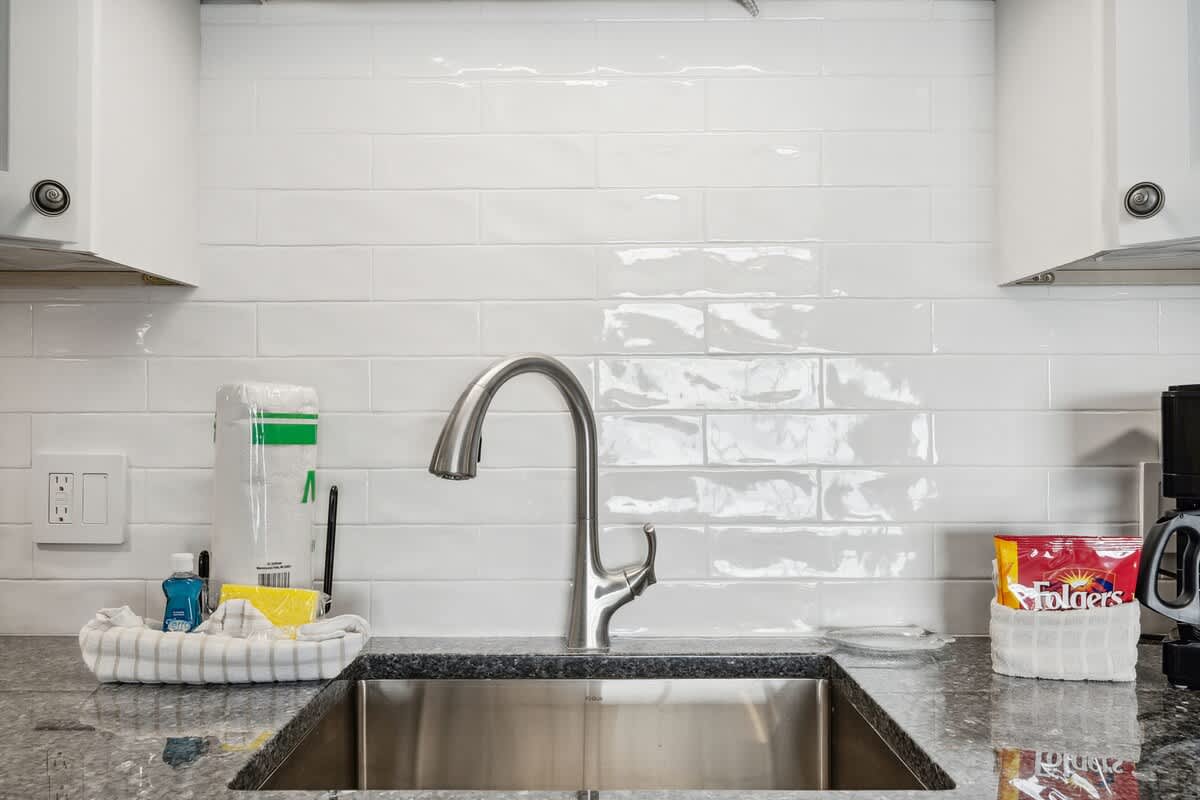 The Summit 602 – Kitchen area featuring stainless steel sink, granite counter, and modern faucet with coffee maker and kitchen supplies visible.