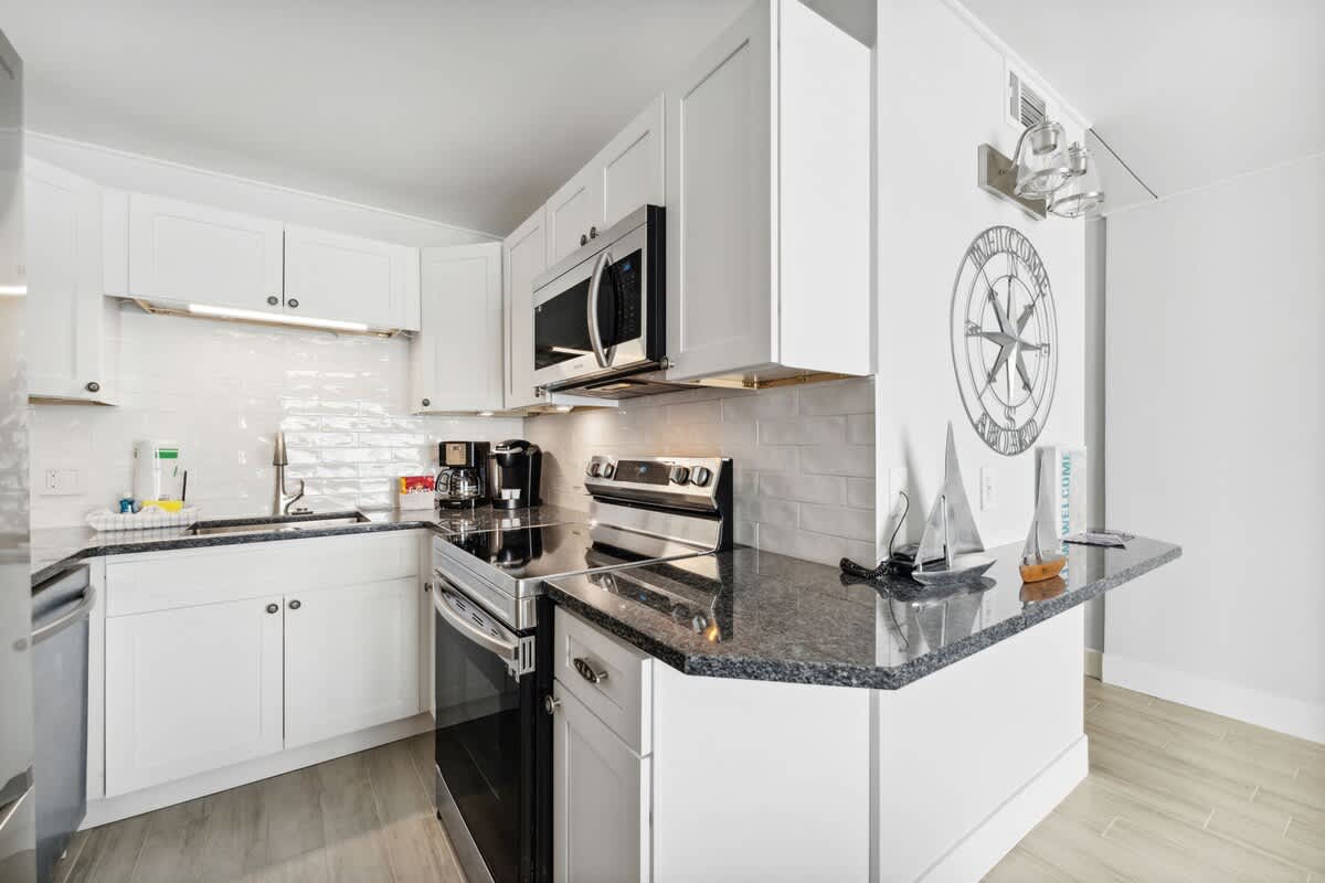 The Summit 602 – Bright kitchen with white cabinets, granite countertops, stainless steel appliances, and decorative nautical accents.