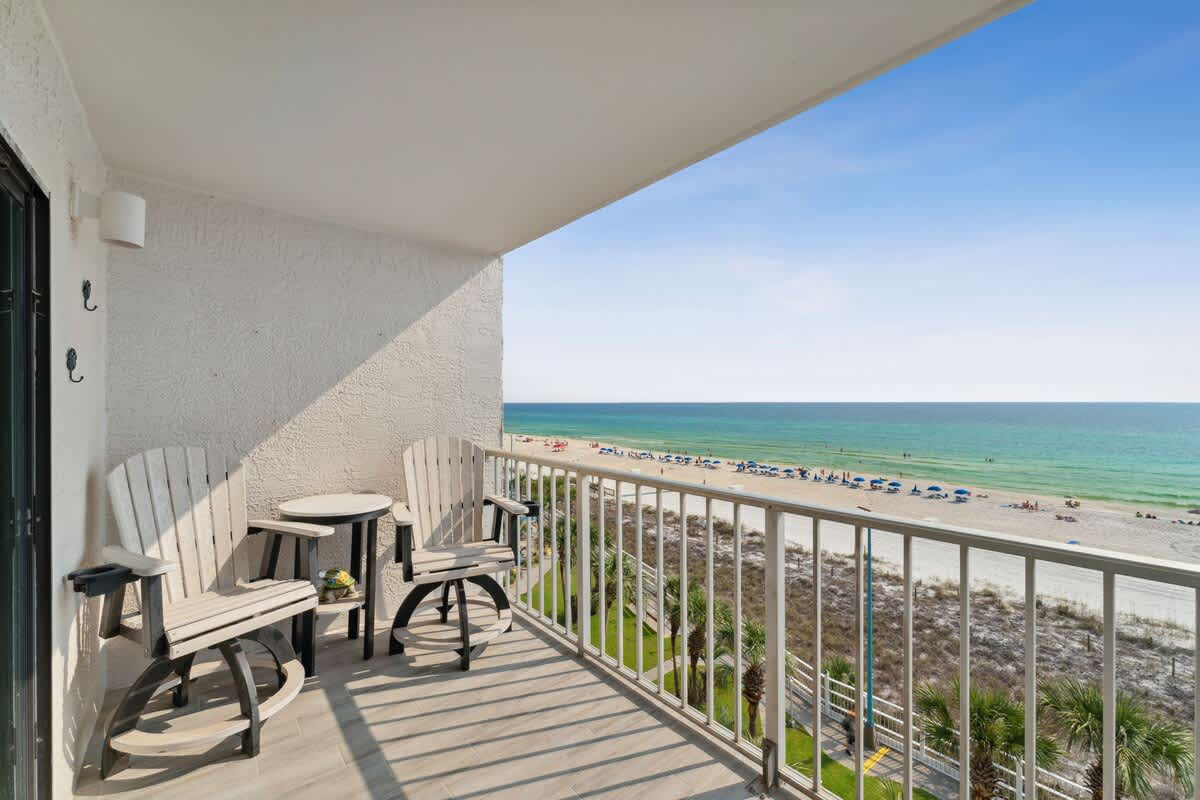 The Summit 602 – Balcony with two chairs and a table overlooking the beach and ocean.