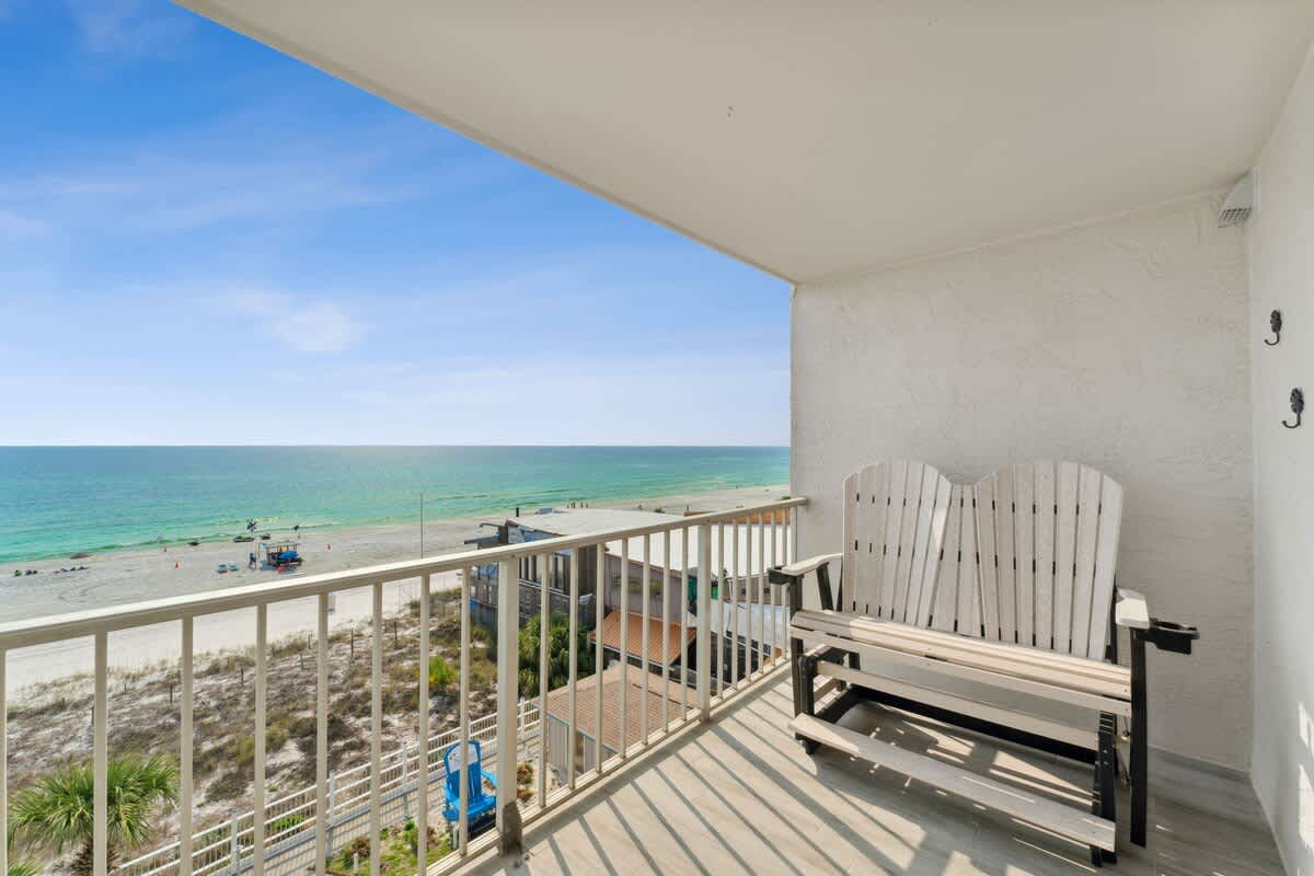 The Summit 602 – Ocean view balcony with wooden seating overlooking beach and turquoise water.