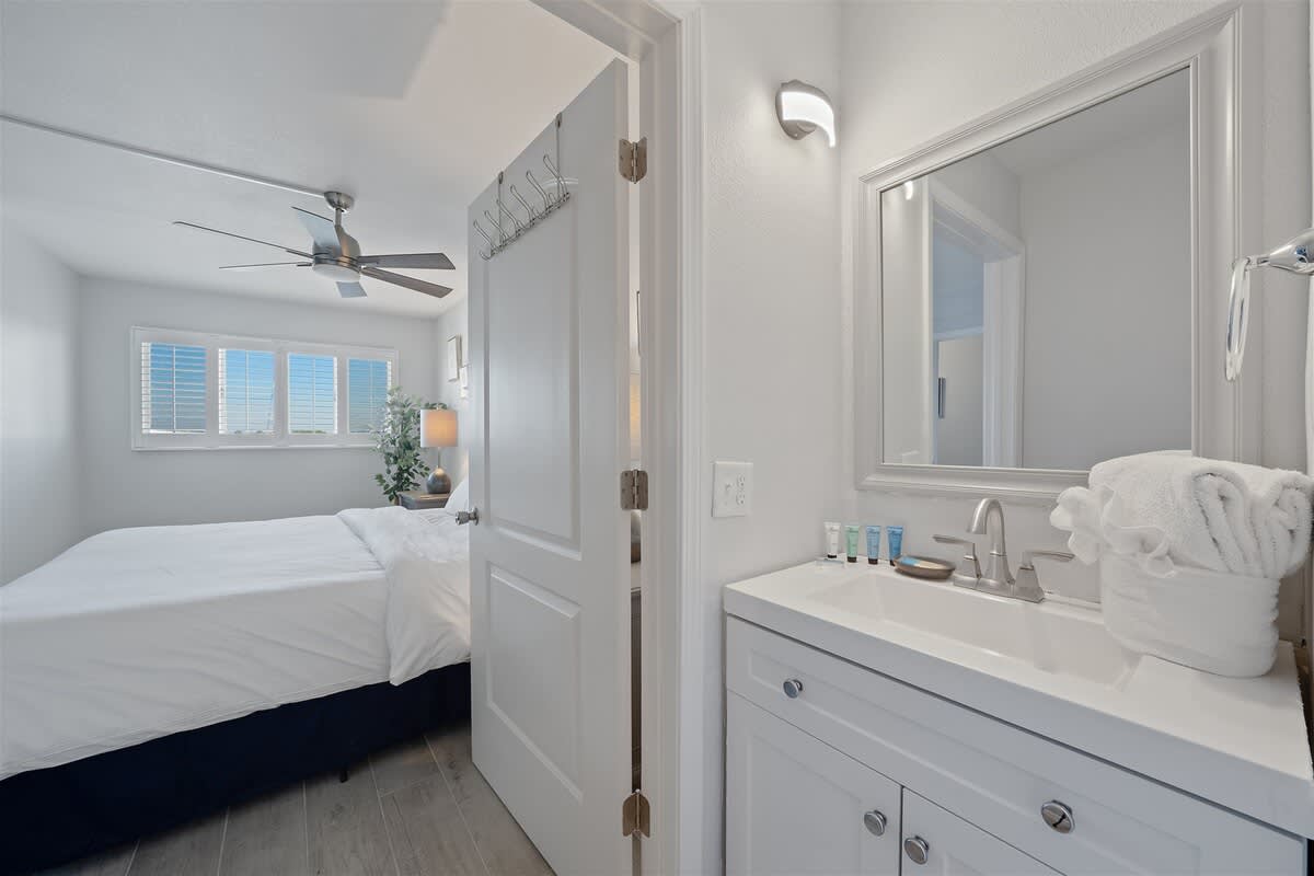 The Summit 621 – Bedroom with a bed, ceiling fan, plant, and a bathroom sink with toiletries.