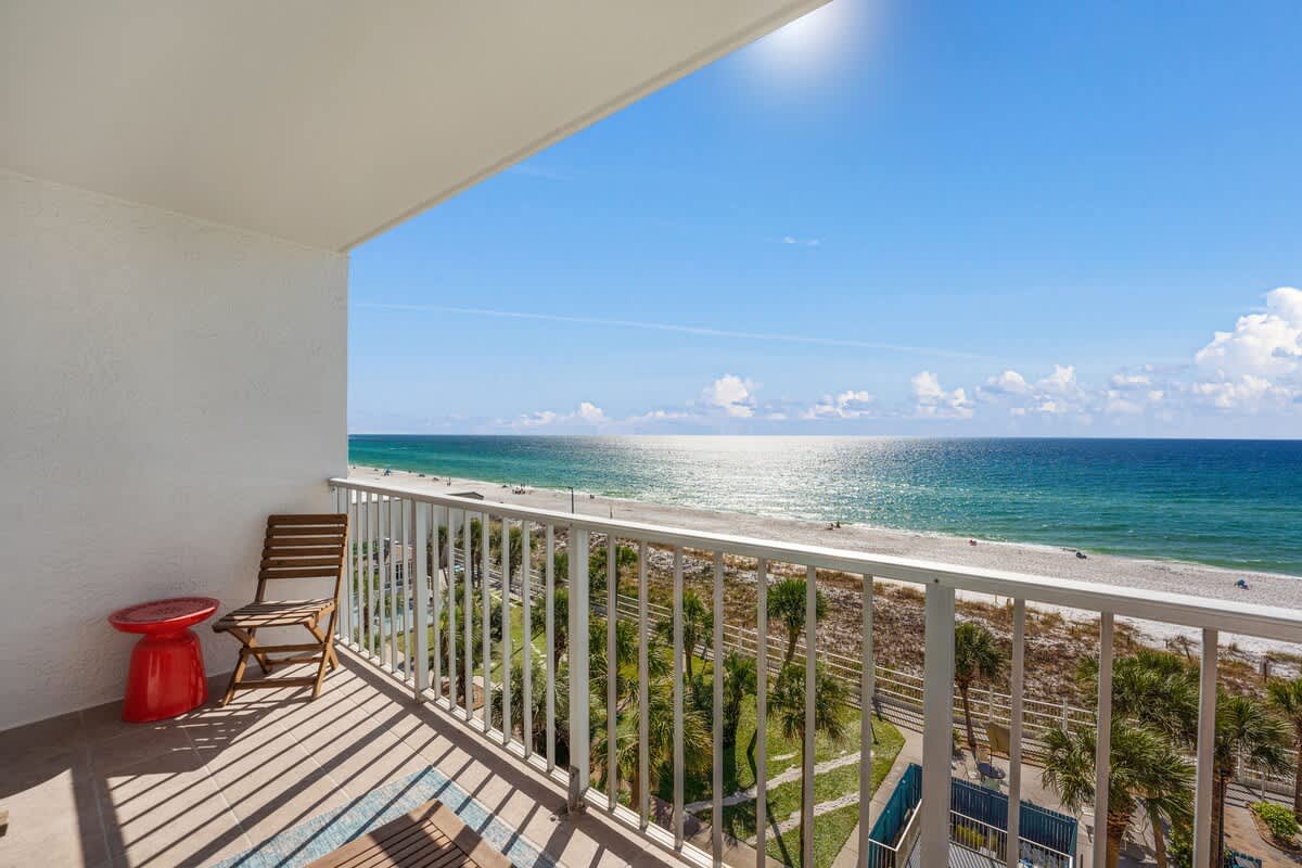The Summit 624 – Balcony view of ocean, with two chairs and small red table.