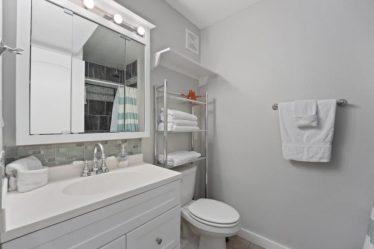 The Summit 624 – Compact bathroom with mirrored cabinet, white sink, towel rack, and shower curtain with blue stripes.