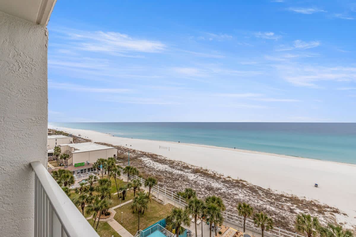 The Summit 820 – View from balcony overlooking the beach and ocean, with palm trees below.