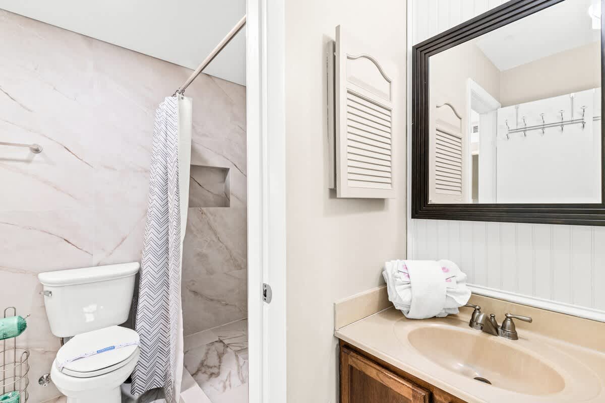 The Summit 820 – Compact bathroom featuring a shower, toilet, sink, and large mirror with decorative trim.