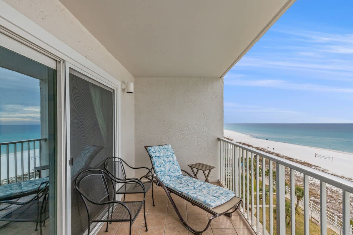 The Summit 820 – Balcony view with a chaise lounge and two chairs overlooking the beach and ocean.