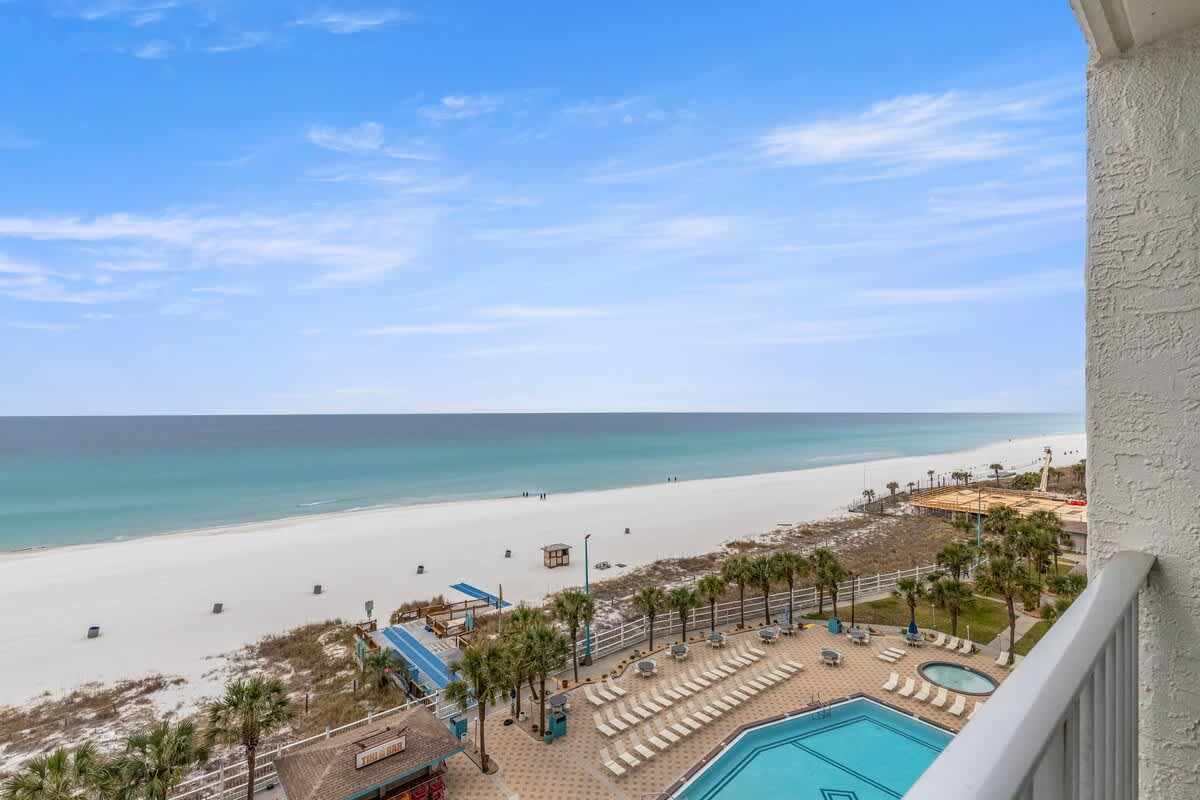 The Summit 820 – Beach view with turquoise water, white sand, palm trees, and a pool area below.