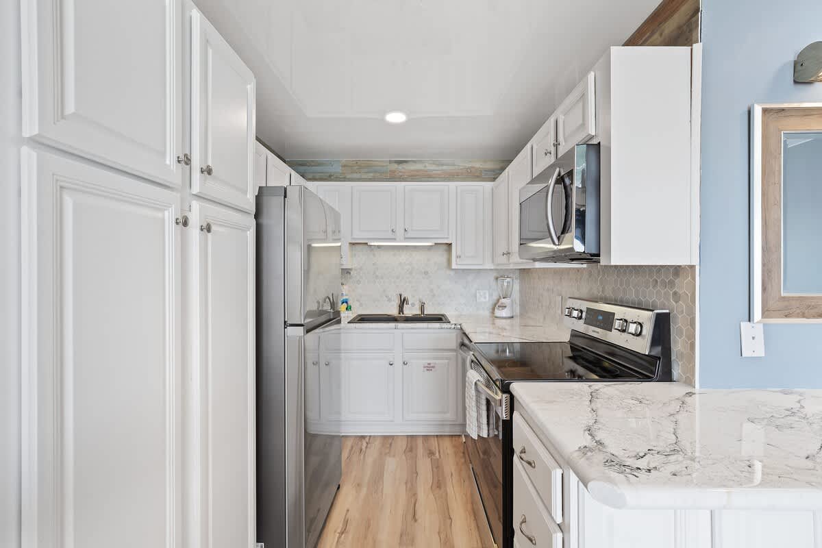 The Summit 1408 – Kitchen with white cabinets, stainless steel appliances, and marble countertops.