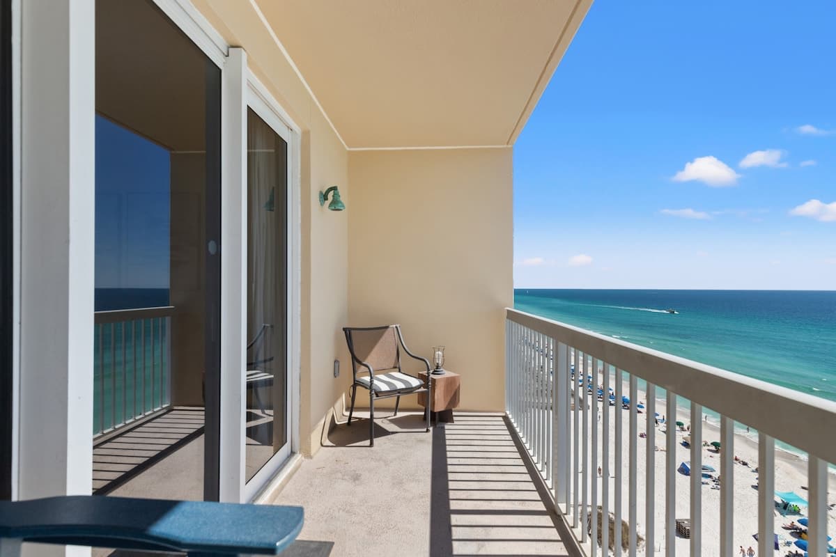Seychelles 1006 – Balcony with ocean view, featuring a chair and small table, overlooking sandy beach and blue water.