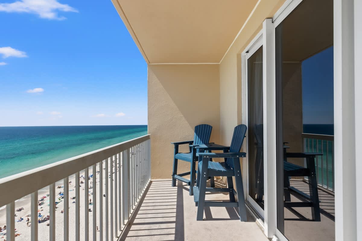 Seychelles 1006 – Balcony view with two blue chairs overlooking beach and ocean.