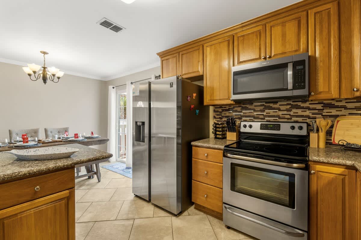 7405 Beach Dr A – Kitchen with stainless steel appliances, granite countertops, wooden cabinets, and a dining area with a table.