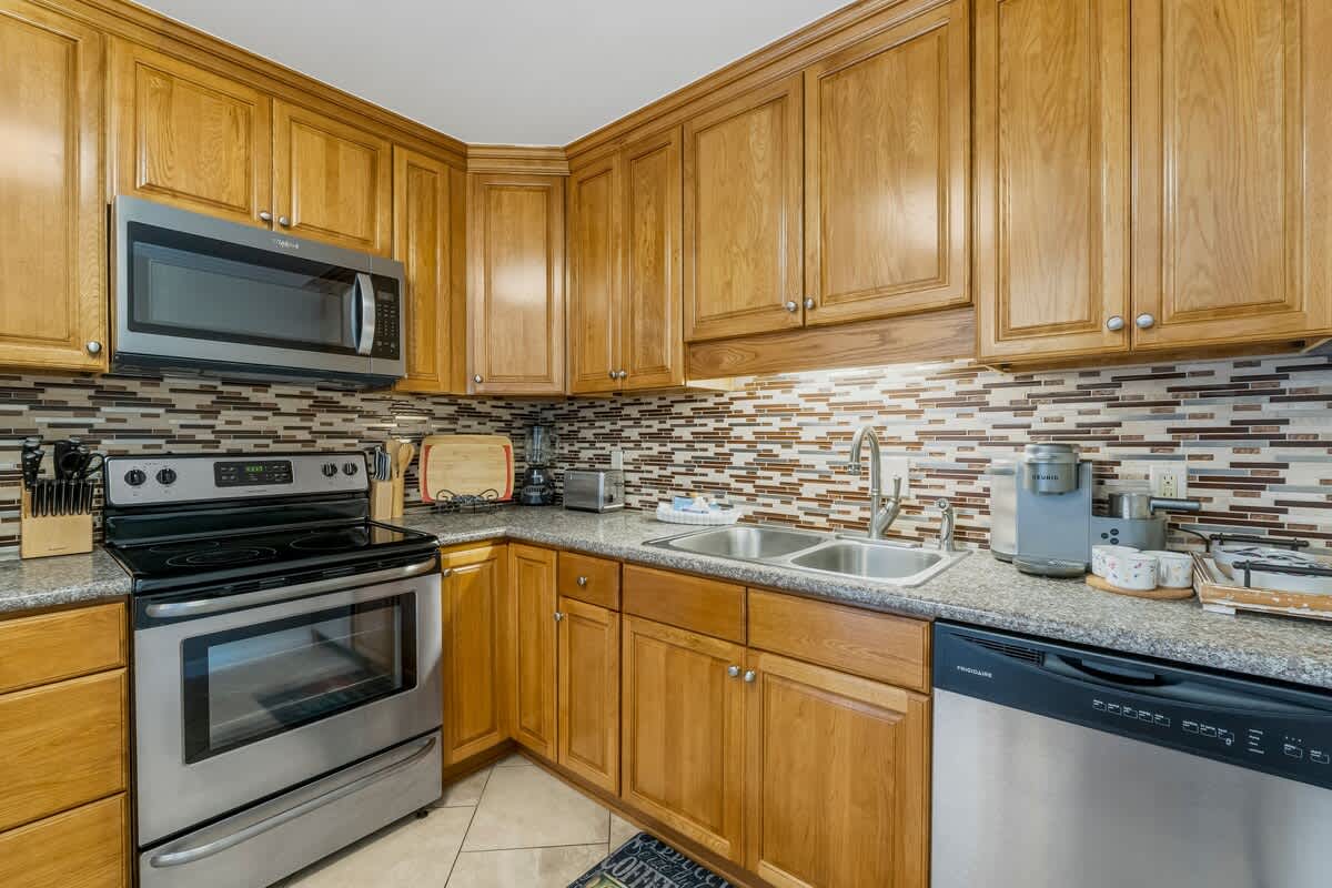 7405 Beach Dr A – Modern kitchen with wooden cabinets, stainless steel appliances, and granite countertops.