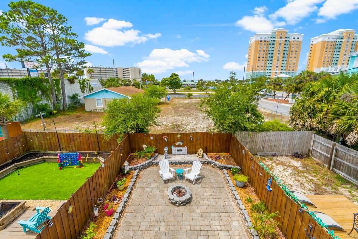 7405 Beach Dr A – Backyard with patio seating, fire pit, grassy area, and surrounding fence.