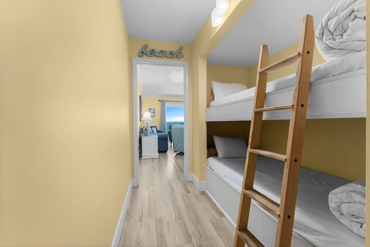 The Summit 726 – Bunk bed area with yellow walls, wooden ladder, and view toward a living space.