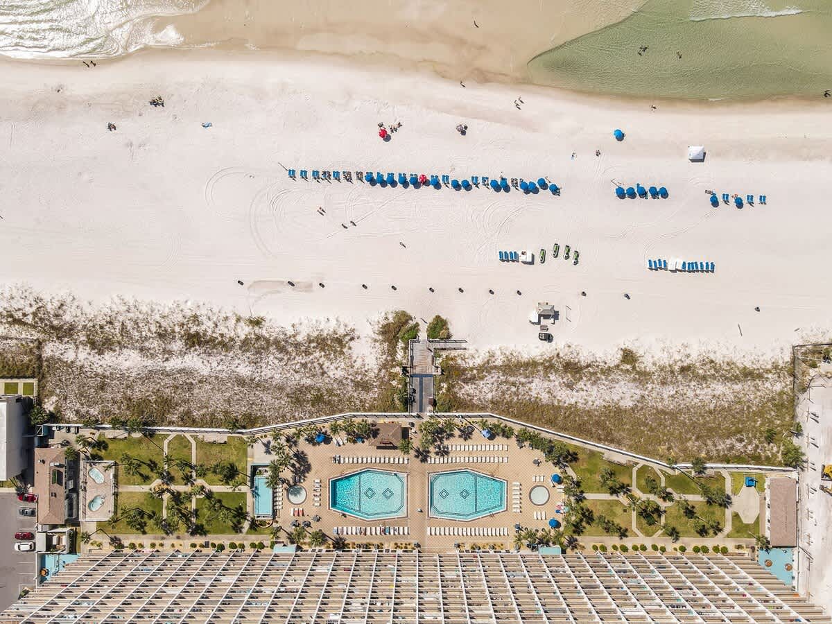 The Summit 726 – Aerial view of pools, beach umbrellas, and sandy beach at The Summit 726 vacation rental.