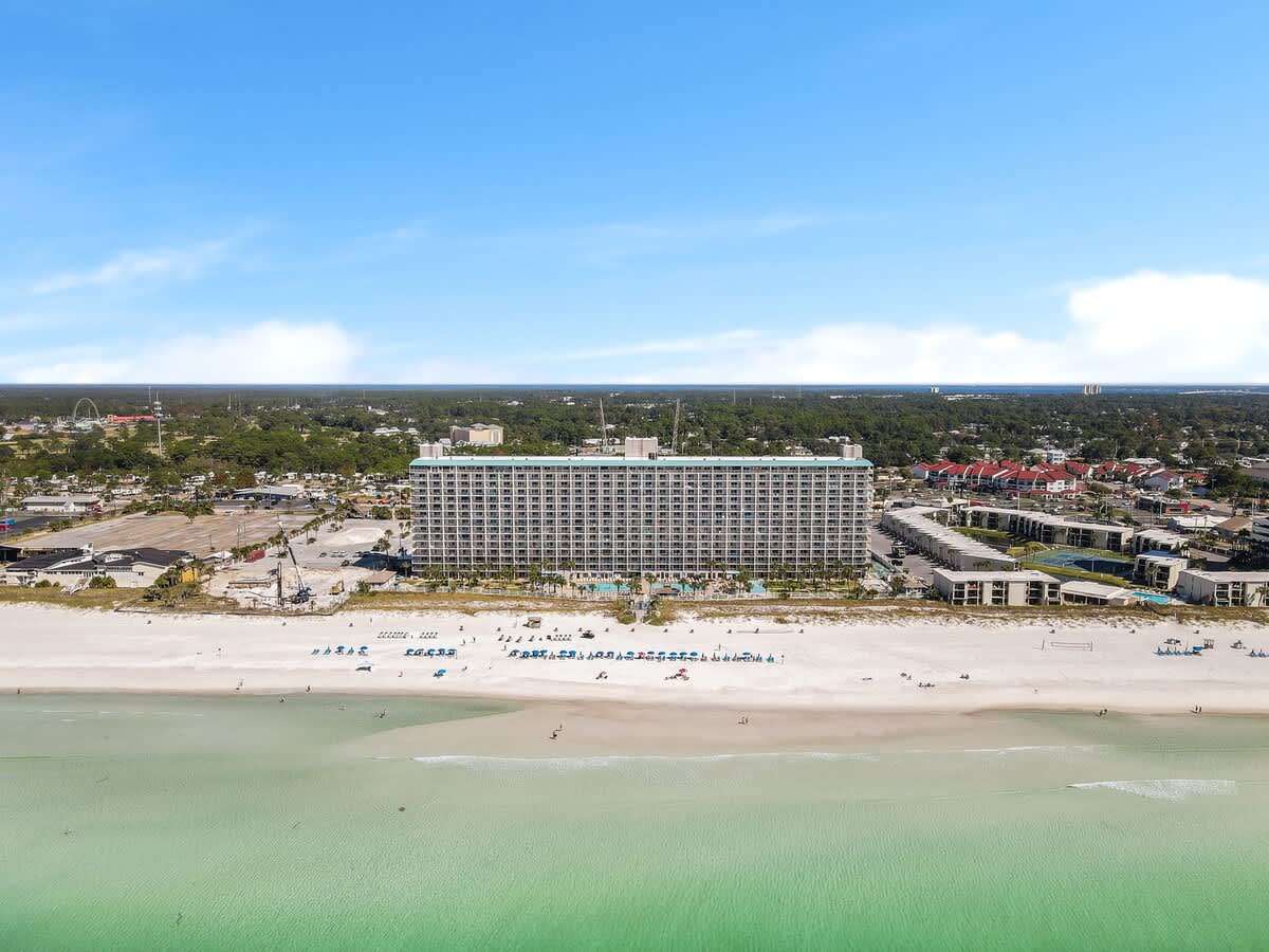 The Summit 726 – Aerial view of a large hotel near a sandy beach and turquoise water.