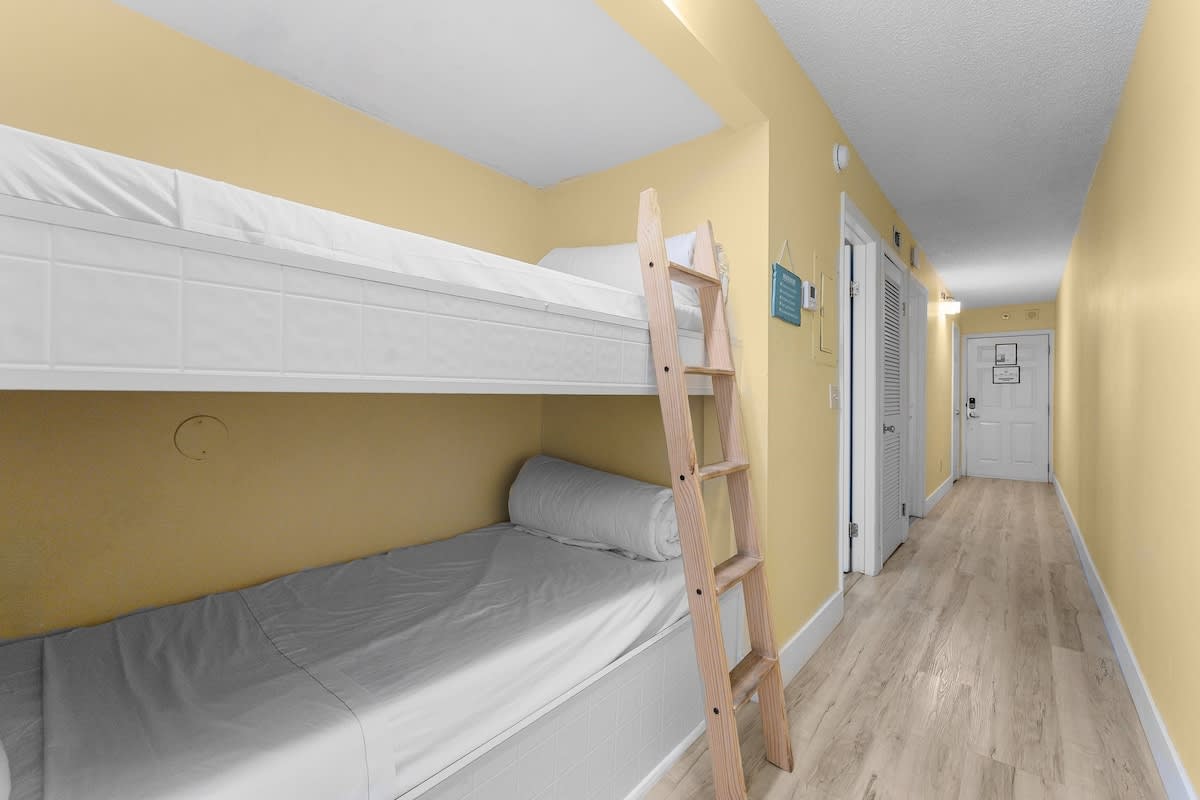 The Summit 726 – Bunk bed with ladder in a hallway with yellow walls and light wood flooring.