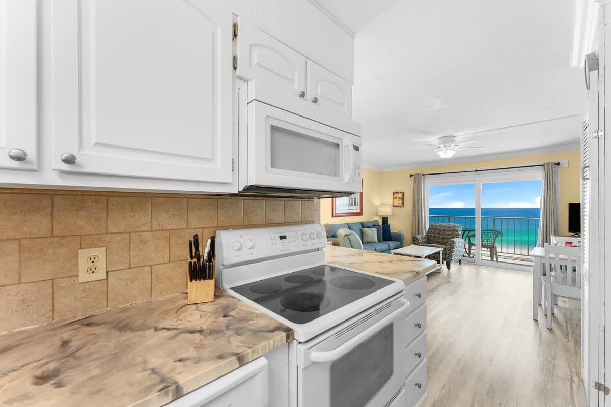The Summit 726 – Kitchen and living area with ocean view, including a couch, chairs, and white cabinetry.