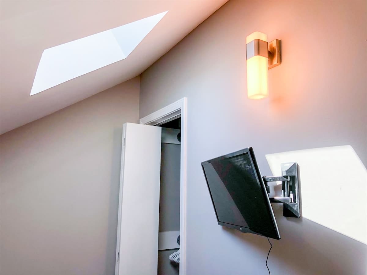 5218 Beach Dr B – Room with a skylight, mounted TV, and wall sconce, with an open closet door.
