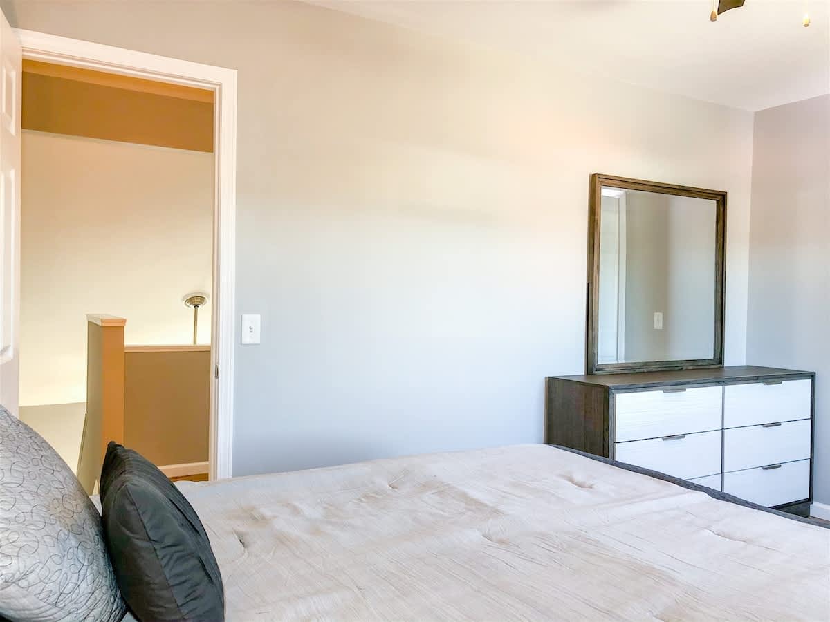 5218 Beach Dr B – Bedroom with gray walls, a bed with black pillows, a dresser, and a mirror.