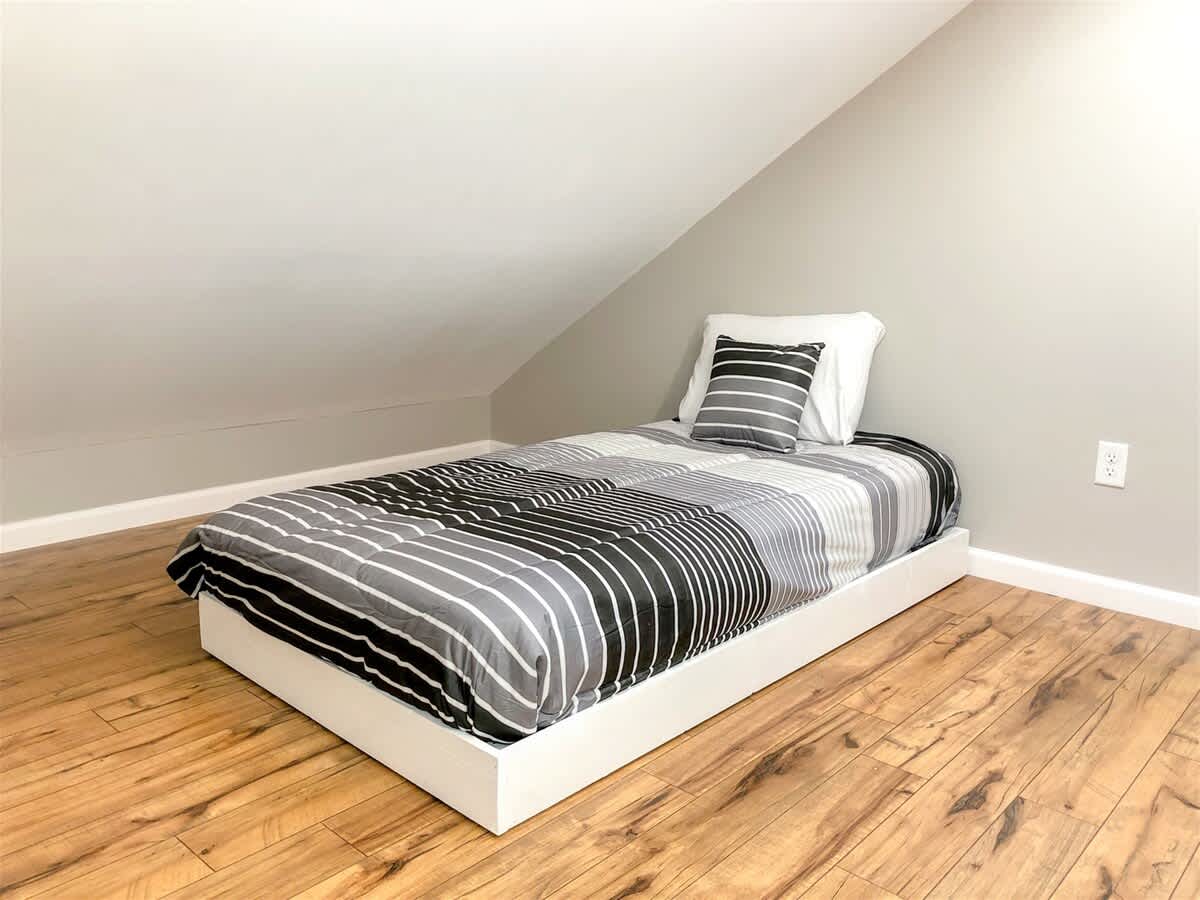 5218 Beach Dr B – Attic bedroom with a single bed, striped bedding, and wooden flooring.
