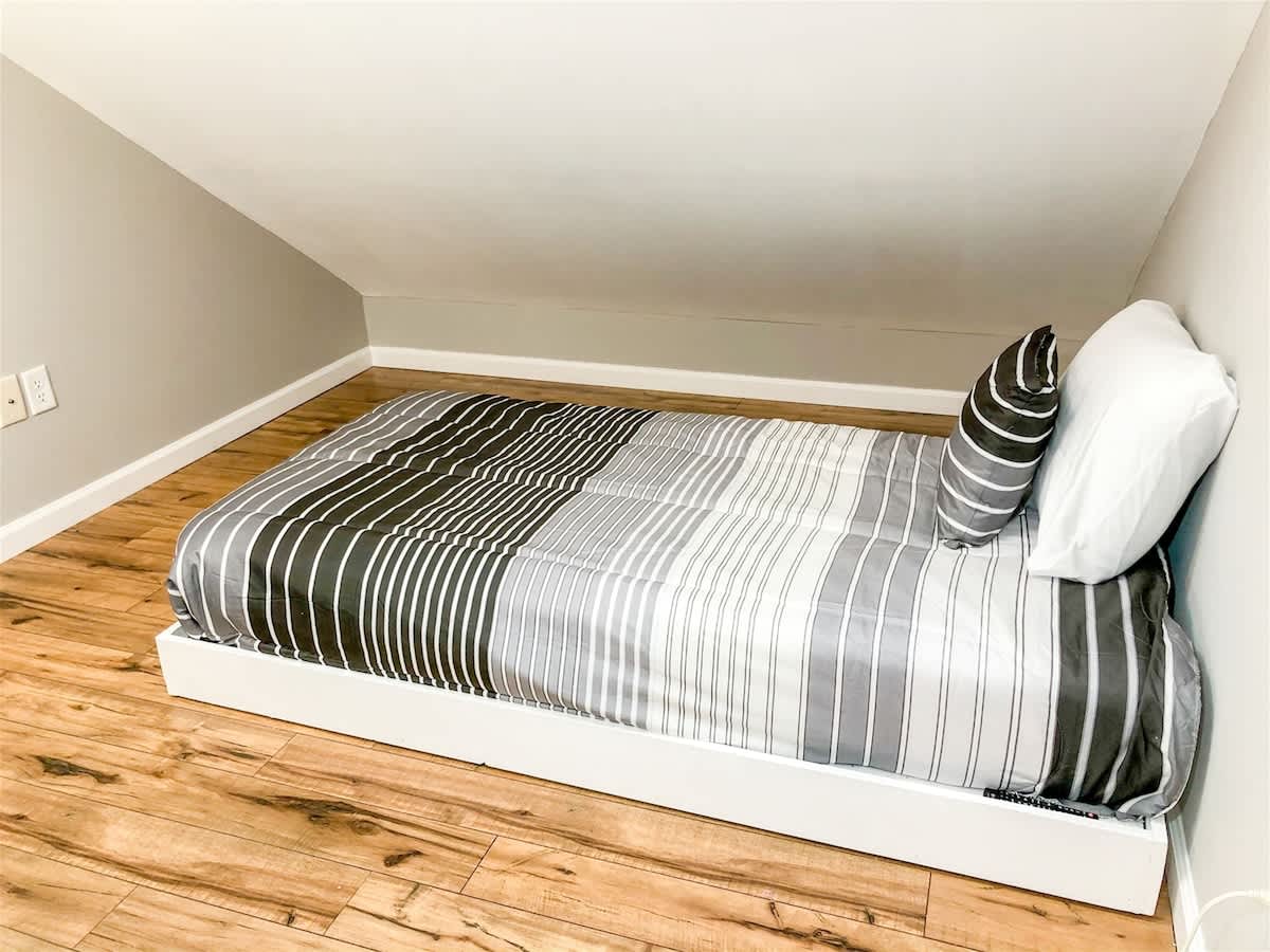 5218 Beach Dr B – Attic bedroom with a single bed, gray striped bedding, and hardwood flooring.