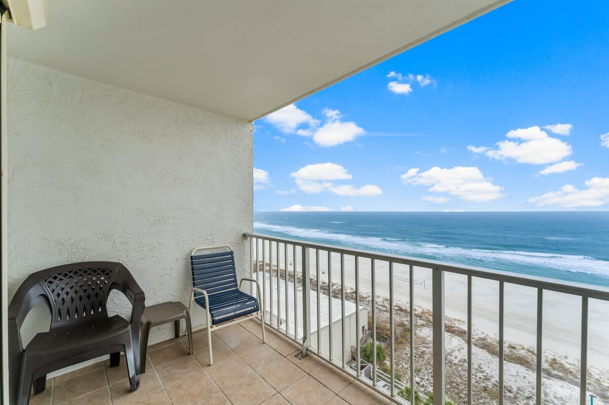 The Summit 1031 – Balcony view with two chairs overlooking sandy beach and ocean.