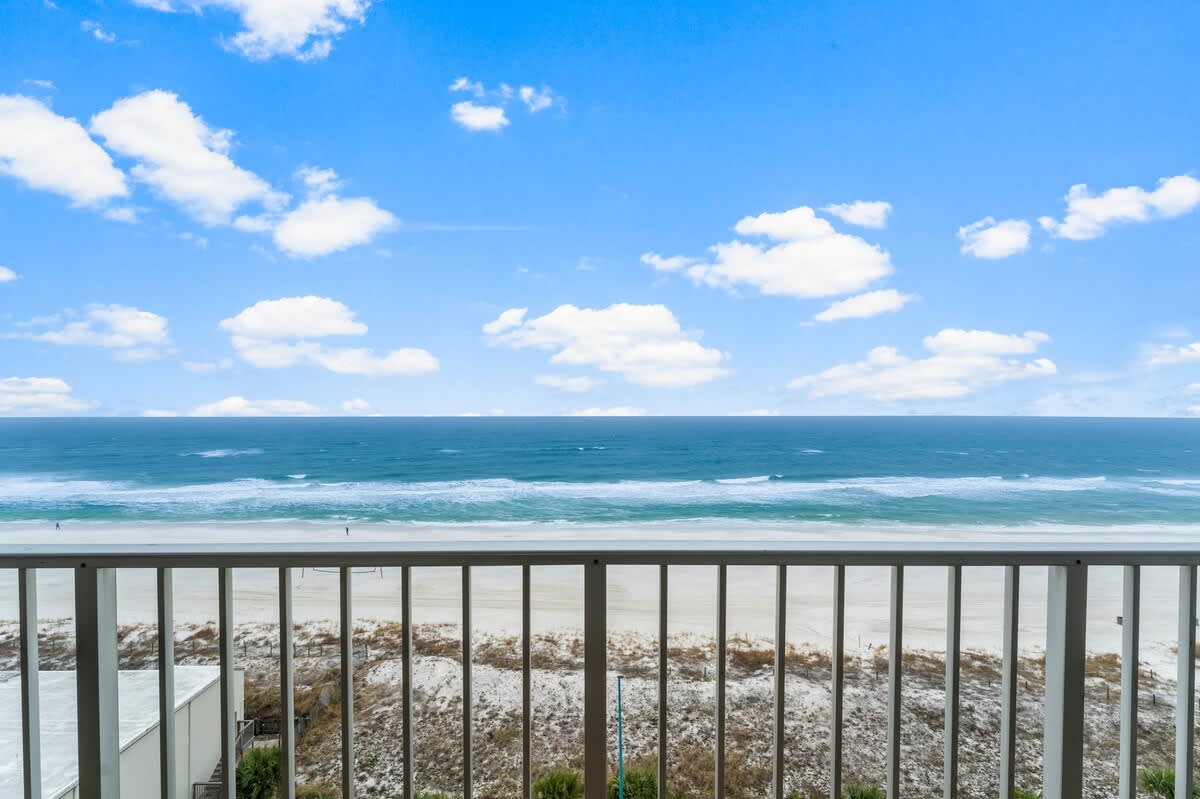 The Summit 1031 – View from balcony overlooking the beach and ocean with blue skies and clouds.
