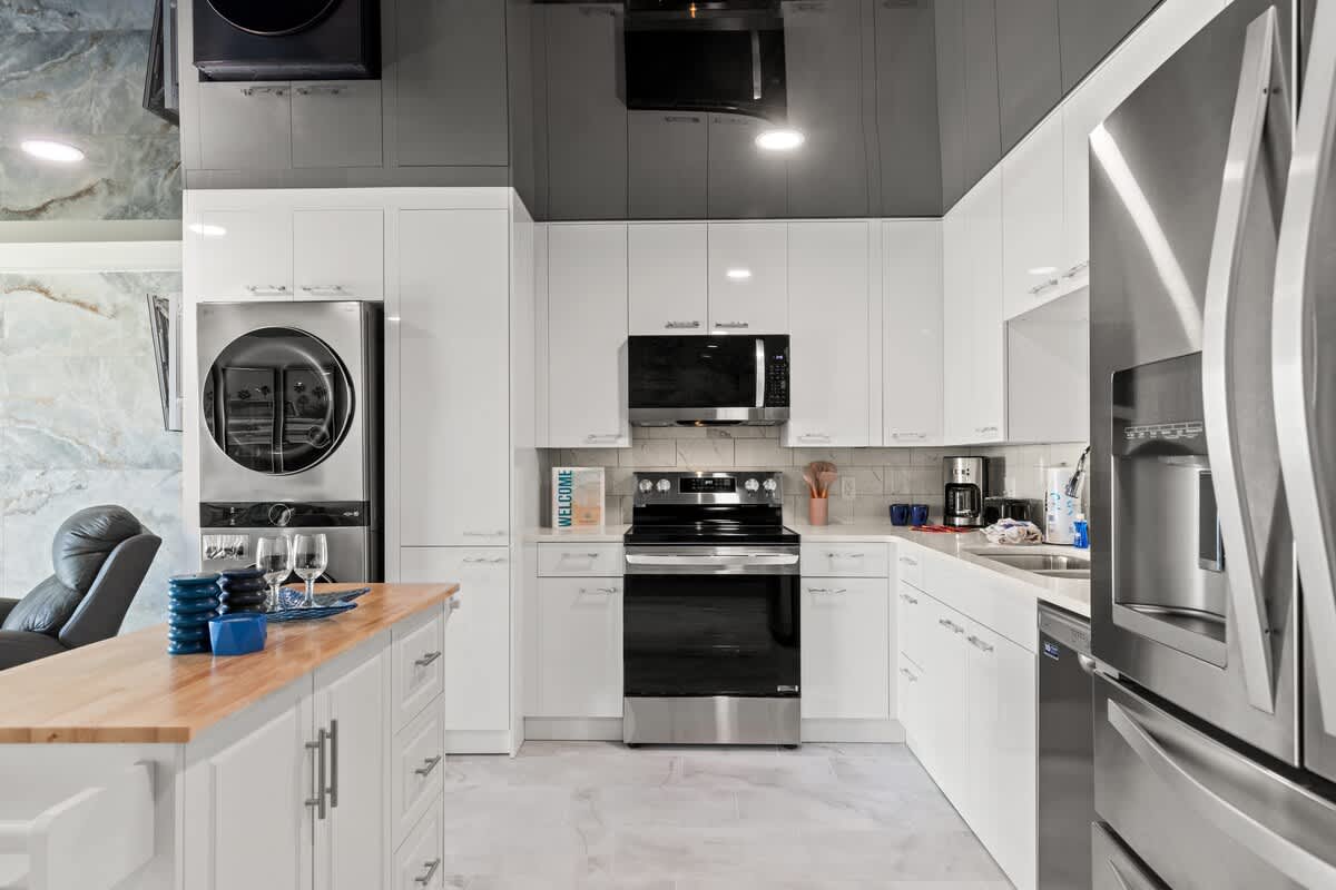 The Summit 306 – Modern kitchen with stainless steel appliances, white cabinets, and a breakfast bar.