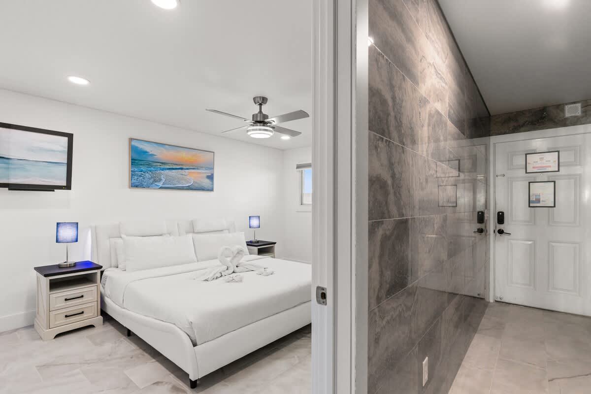 The Summit 306 – Bedroom with a queen bed, artwork, nightstands, ceiling fan, and an entrance door.