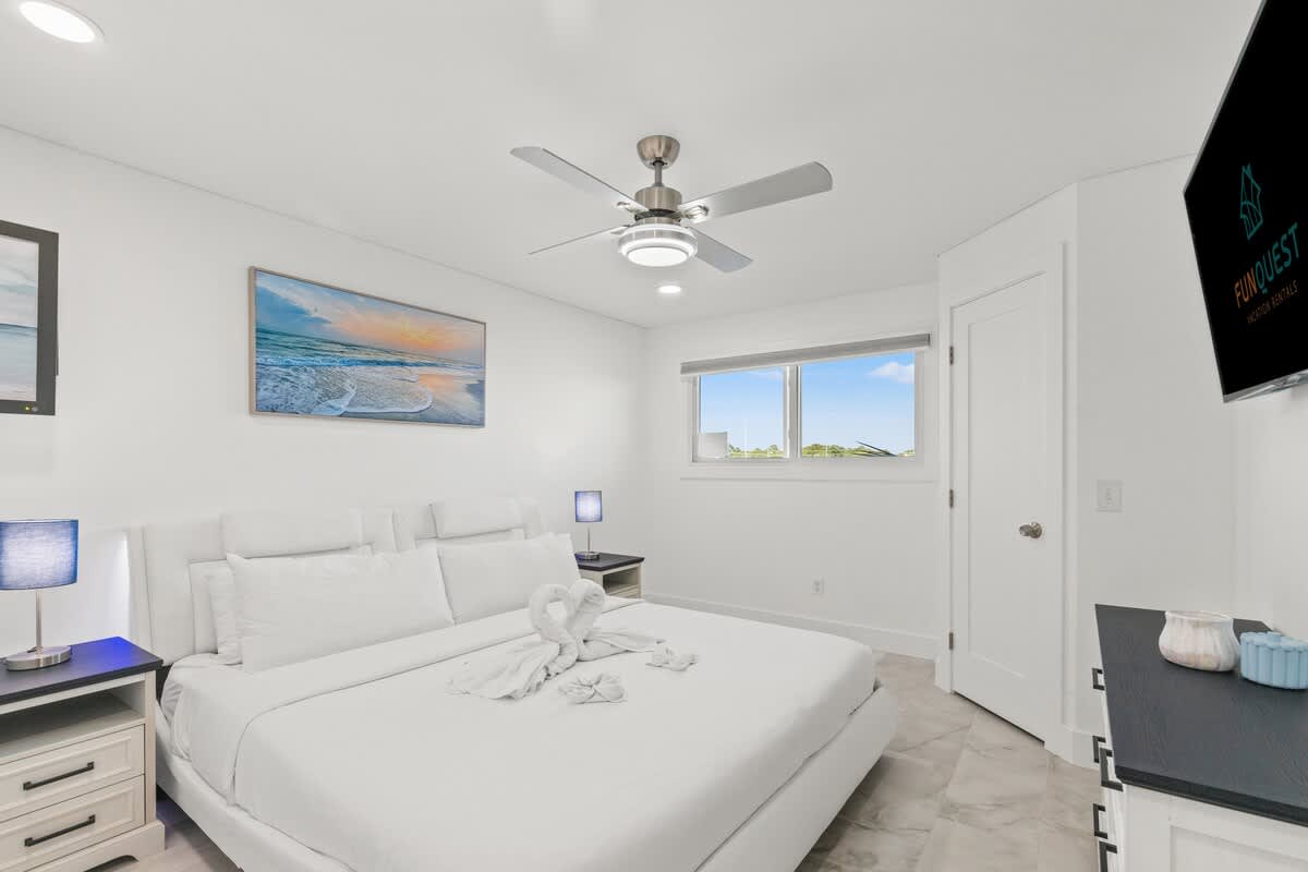 The Summit 306 – Bright bedroom with a queen bed, ceiling fan, TV, and window revealing outdoor view.