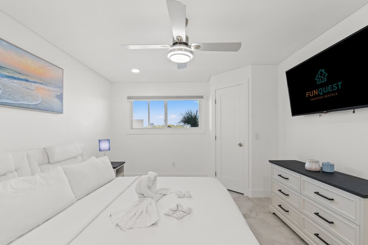 The Summit 306 – Bright bedroom with a king bed, TV, dresser, window with view, and a ceiling fan.
