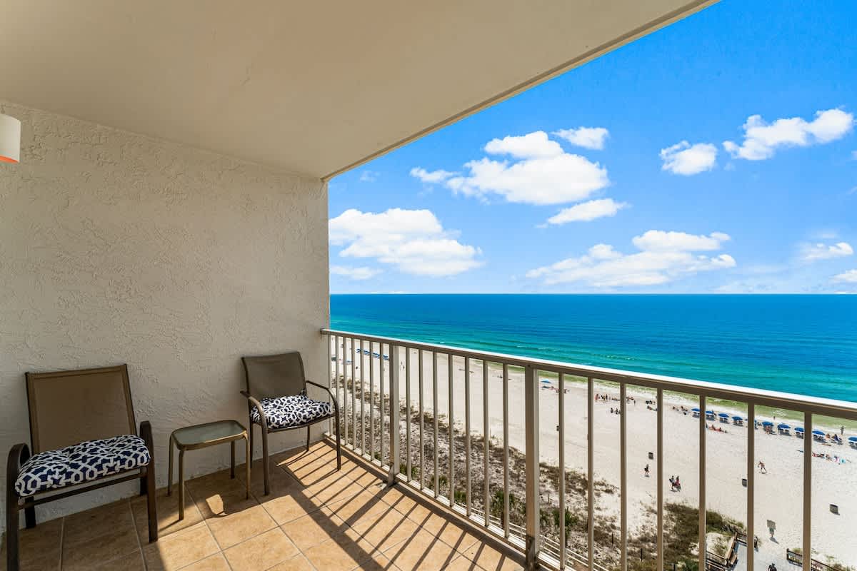 The Summit 1116 – Balcony view of beach and ocean, featuring two chairs and a small side table.