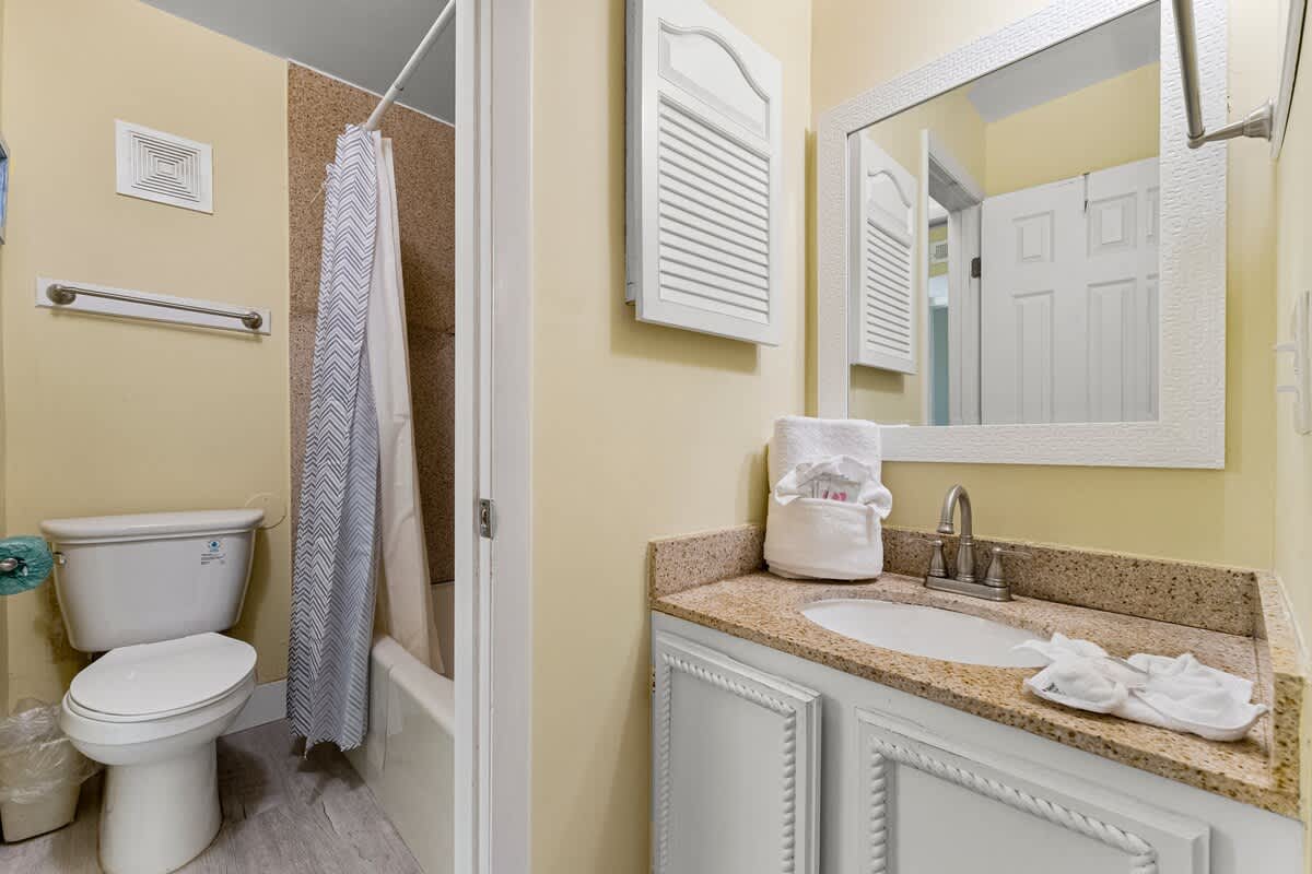 The Summit 1116 – Bathroom featuring a bathtub, shower curtain, sink with granite countertop, and white towels on the counter.