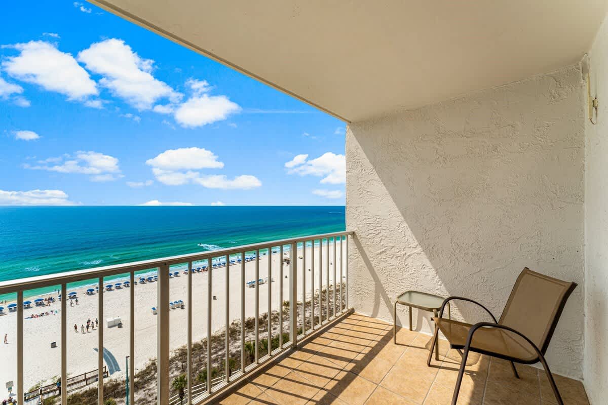 The Summit 1116 – Balcony view of beach with chairs, blue ocean, and clear sky.