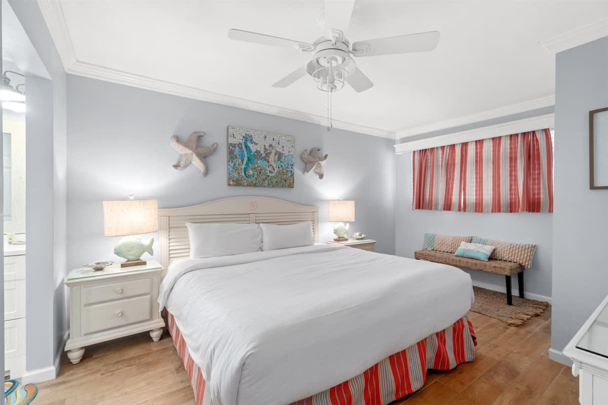 The Summit 502 – Bedroom with a queen bed, nightstands, decorative wall art, and a small bench by the window.