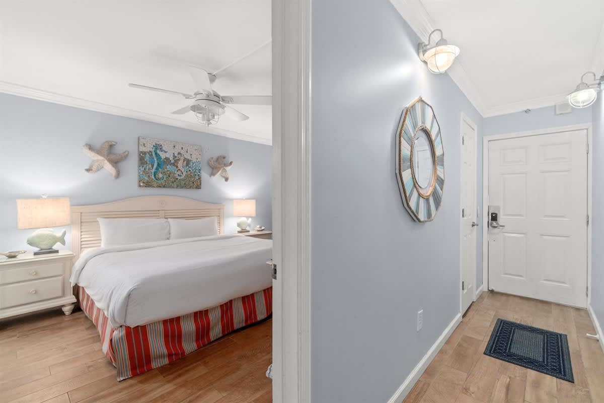 The Summit 502 – Bright bedroom with a king bed, light blue walls, and wooden flooring, featuring decorative sea-themed artwork.