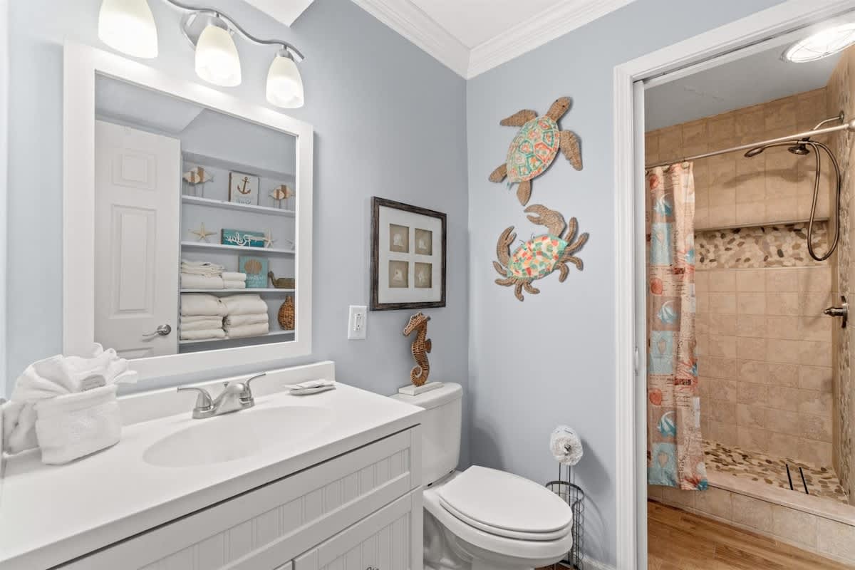 The Summit 502 – Bathroom with white vanity, mirror, decorative sea life, and walk-in shower.