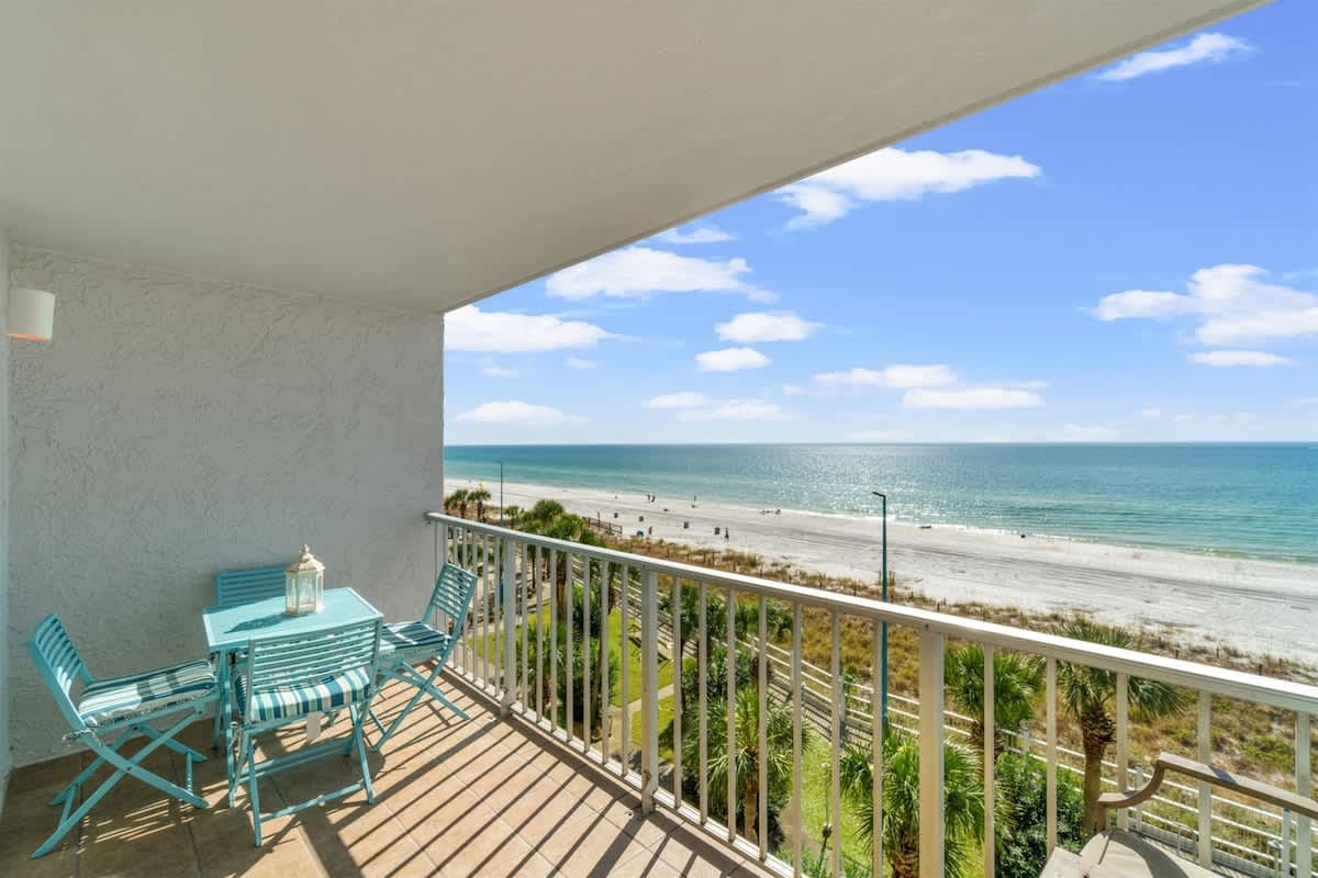 The Summit 502 – Balcony with turquoise furniture overlooking a sandy beach and ocean view.